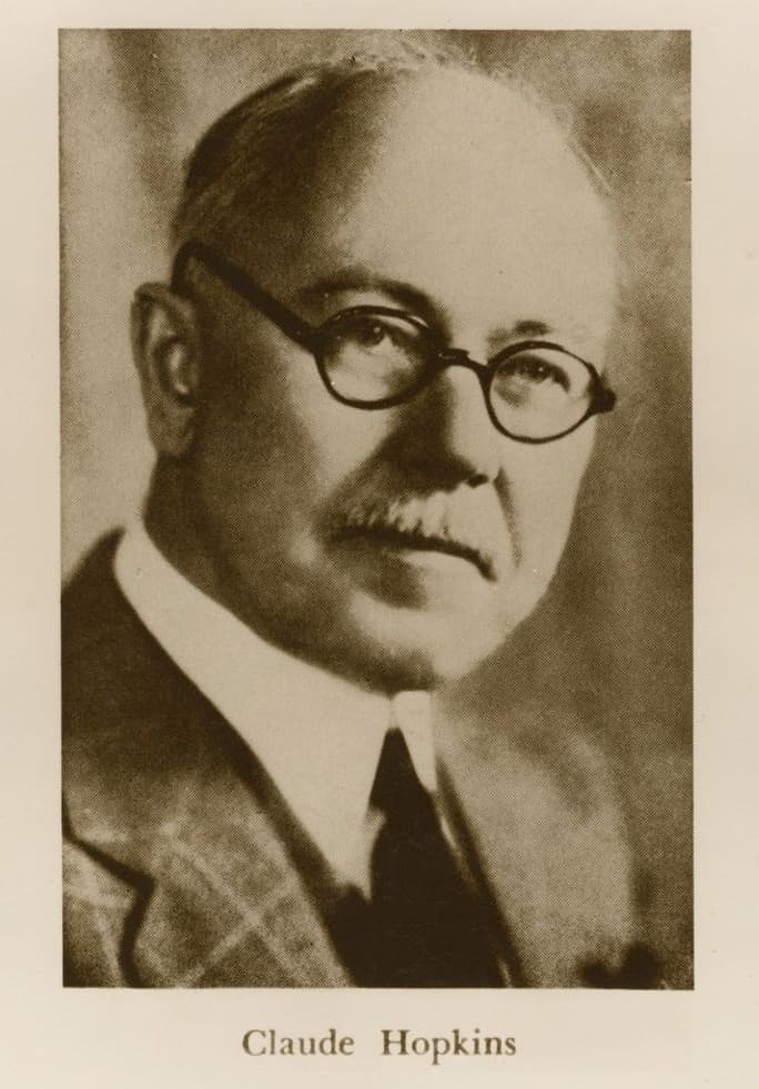 Black and white photographic portrait of Claude Hopkins, author of Scientific Advertising (1923), wearing wire-rimmed glasses and a tweed suit, with his name printed beneath the image.
