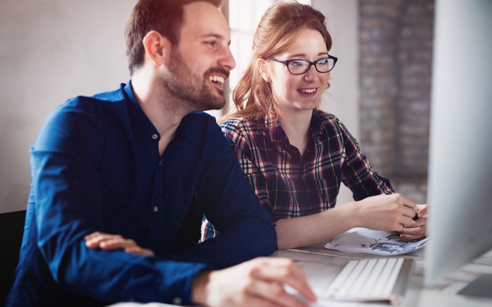 Two coworkers reviewing analytics together at a desk, representing the Whitehot Discoverability Audit offered through Whitehot Studio.